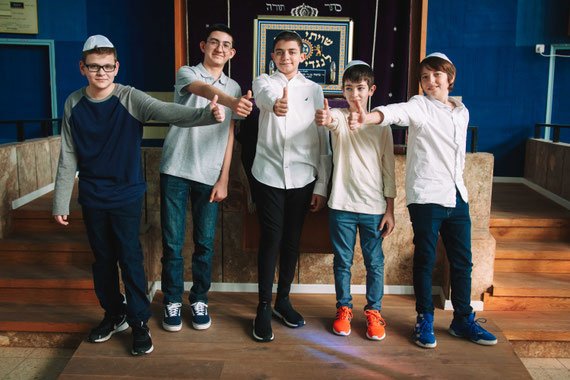חתן בר המצווה עם חברים על רקע היכל ספרי תורה