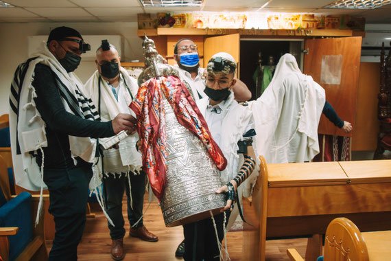 החתן צועד עם ספר התורה